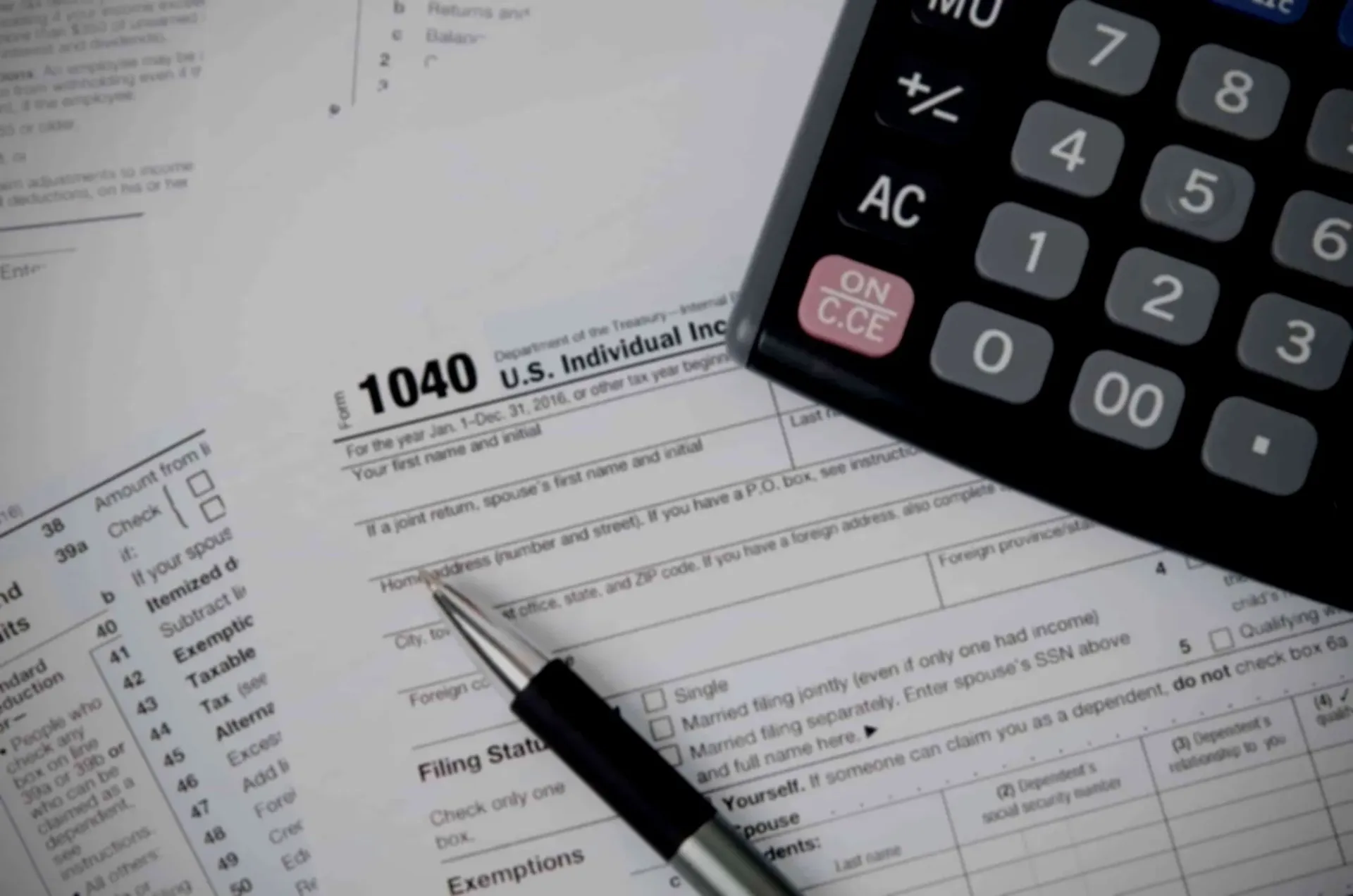 Tax forms, a calculator, and a pen on a desk